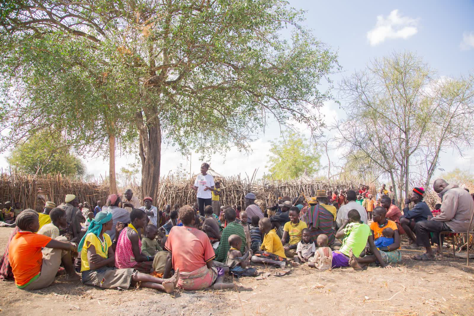 Villagers gathered under a tree for a community meeting